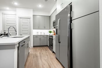 a kitchen with gray cabinets and white countertops